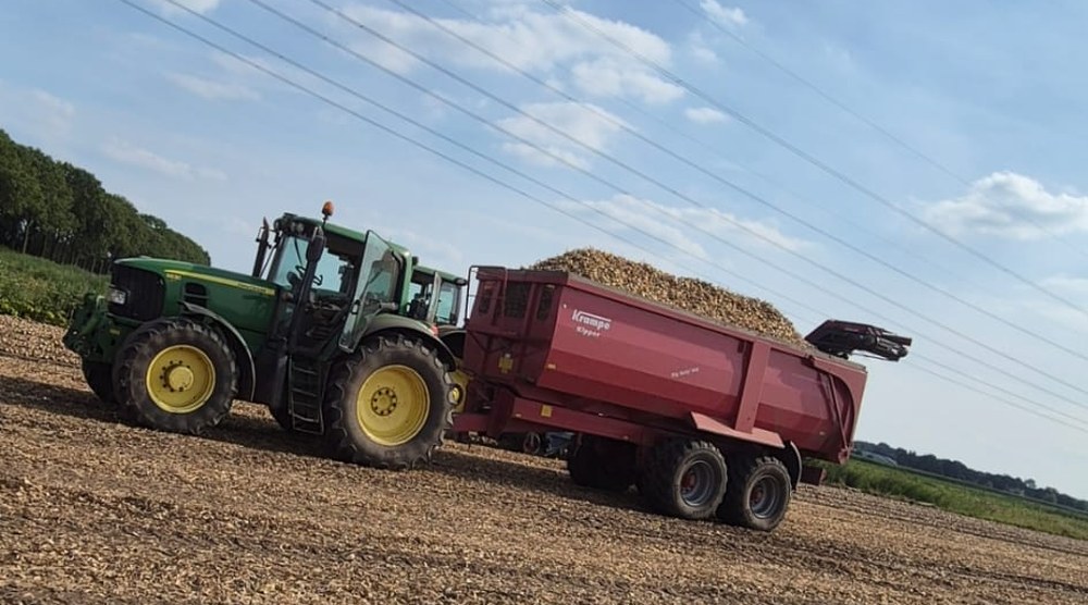 Tractor met kipwagen vol geoogste uien